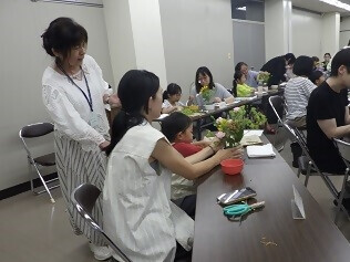 先生にアドバイスをもらいながらお花をいけている子どもの写真