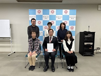 画像：バックボードの前で会長らと撮影した様子