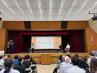 安藤さんと洪さんが壇上で司会者と喋っている写真