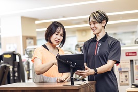 スポーツクラブでインストラクターからアドバイスをうける女性