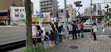 区役所前交差点で、サイン板を掲げて交通安全を呼びかける様子です。
