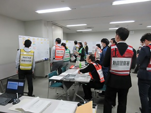 図上訓練でホワイトボードを囲む職員たち