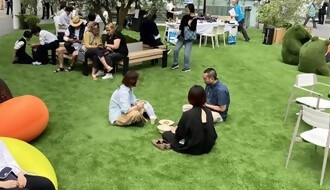 芝やファニチャに座りくつろぐ人々の様子