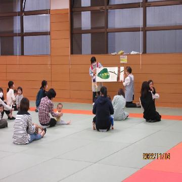 子育てわいわいひろばで、大きな絵本を読んでもらっている写真です。