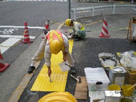 歩道の視覚障害者用点字シート貼り付け作業の様子