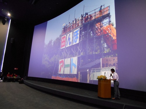 映画館のスクリーンに映しだされる各地の事例発表