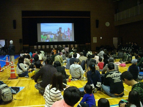 体育館のステージのスクリーンで1年間の映像を上映している