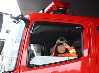 子どもが消防車で敬礼する様子